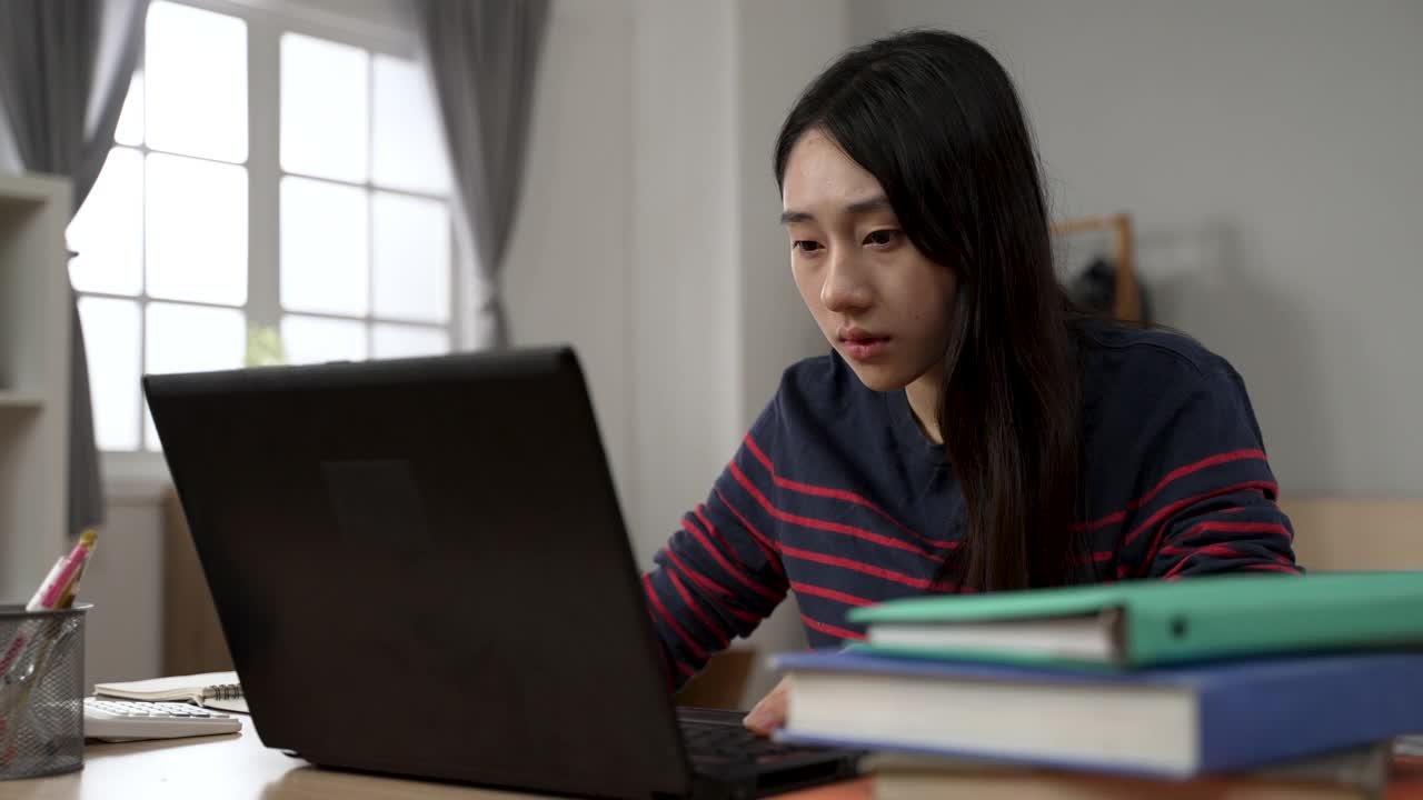 一位台湾女大学生在家里学习时，眼睛突然变得模糊，她靠在笔记本电脑屏幕前，试图看得更清楚视频素材