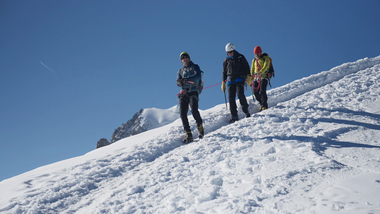 一队登山者正在从陡峭的山峰上下来。使用绳索和攀爬设备视频素材