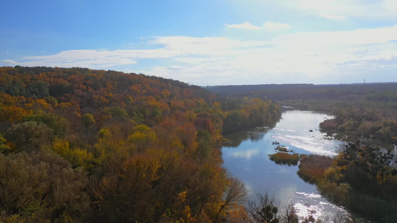 秋天的自然景观。秋高气爽的树木和河流的田园森林全景。橙色，绿色，黄色，红色的叶子，树林的树梢。鸟瞰图视频素材