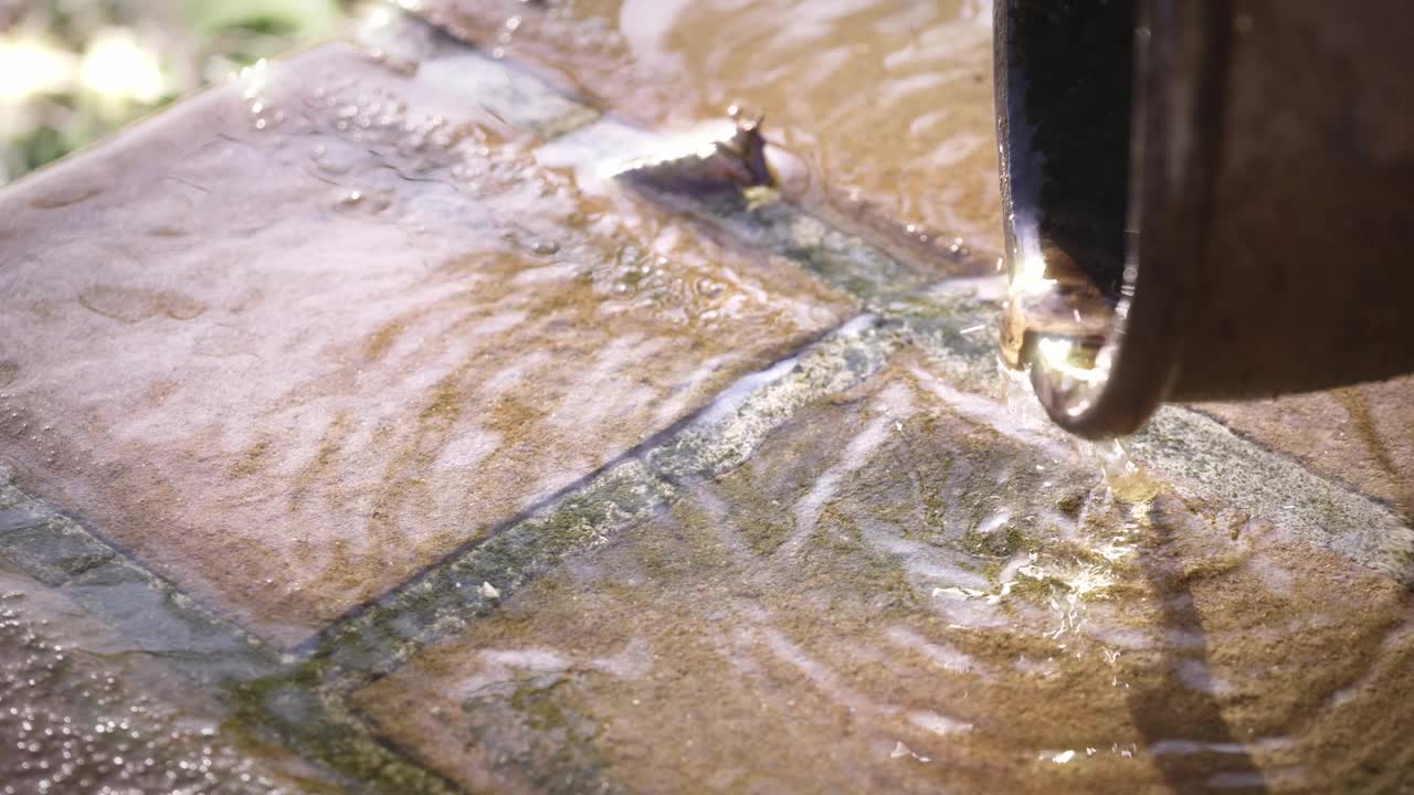 从排水沟滴下的水。雨水流在地面上，是天然的水视频下载