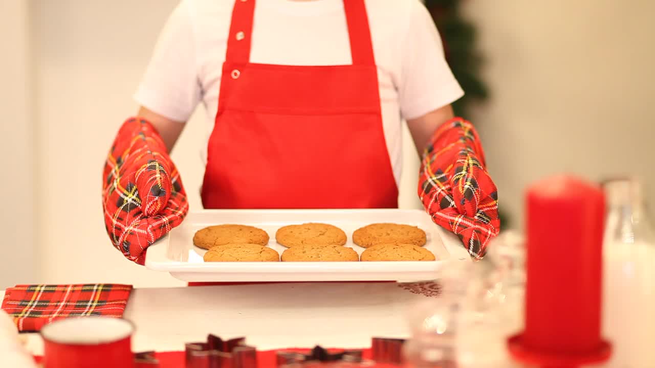 小男孩在家里烤圣诞饼干。孩子拿着烤盘，上面放着现成的饼干视频下载