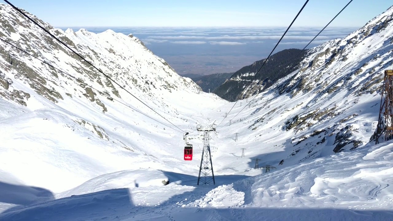 红色缆车爬上冰雪覆盖的高山山谷，把游客带到山顶视频素材