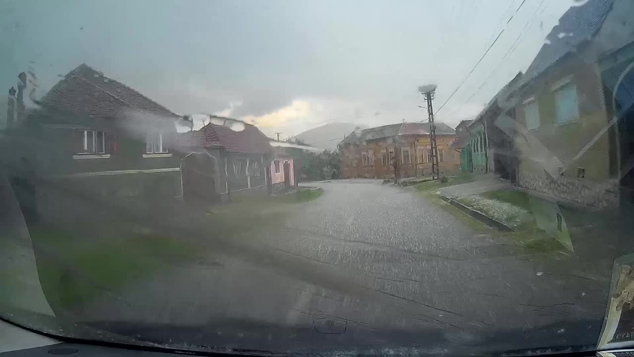 带着冰的雨，连汽车挡风玻璃的雨刷都刮不掉。这辆车在街道上低速行驶，从一个村庄开始，附近的房子一楼有78层视频素材