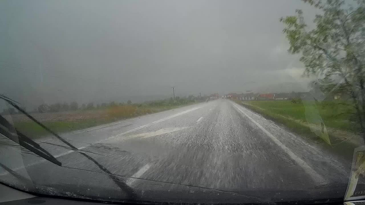 几乎无法清除落在行驶中的汽车前面铺好的路面上的冰雨的雨刮器视频素材