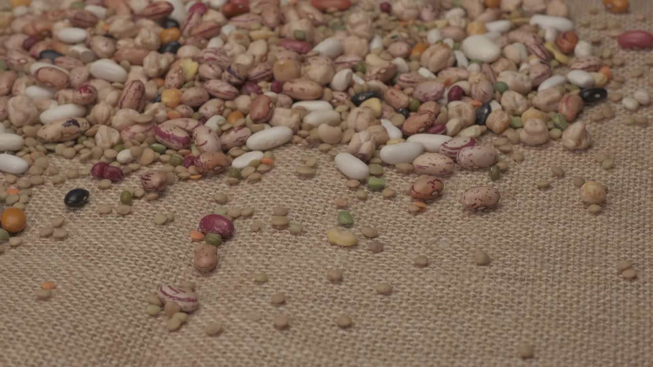 在黄麻背景上旋转的干豆科植物。豆类健康蛋白质饮食，地中海素食素食营养视频素材