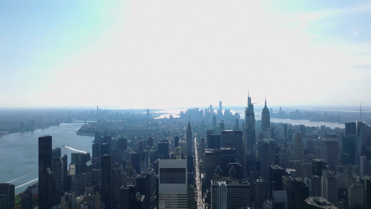 鸟瞰被水包围的岛屿上的城市全景。市中心的摩天大楼映衬着明亮的天空。曼哈顿，美国纽约市视频素材