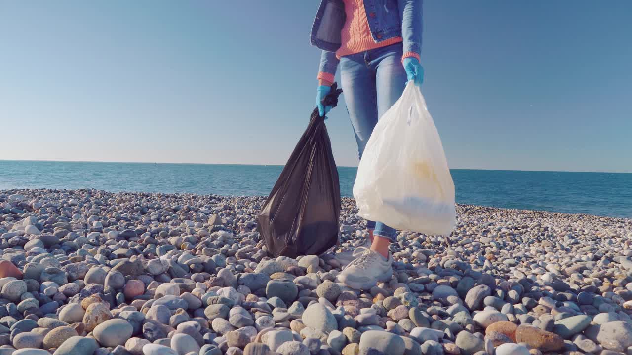 一位女性志愿者用黑色垃圾袋收集垃圾。视频素材