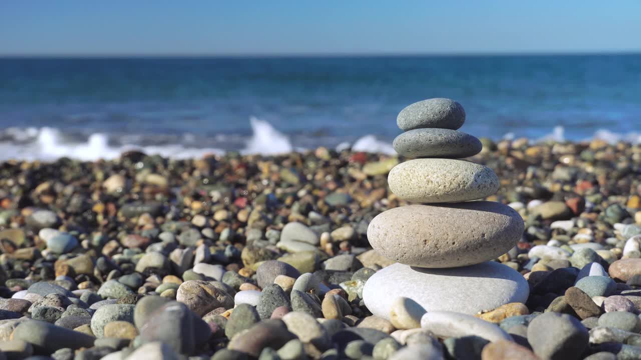 金字塔的石头在一个阳光明媚的日子在蓝色的海洋背景上。视频素材