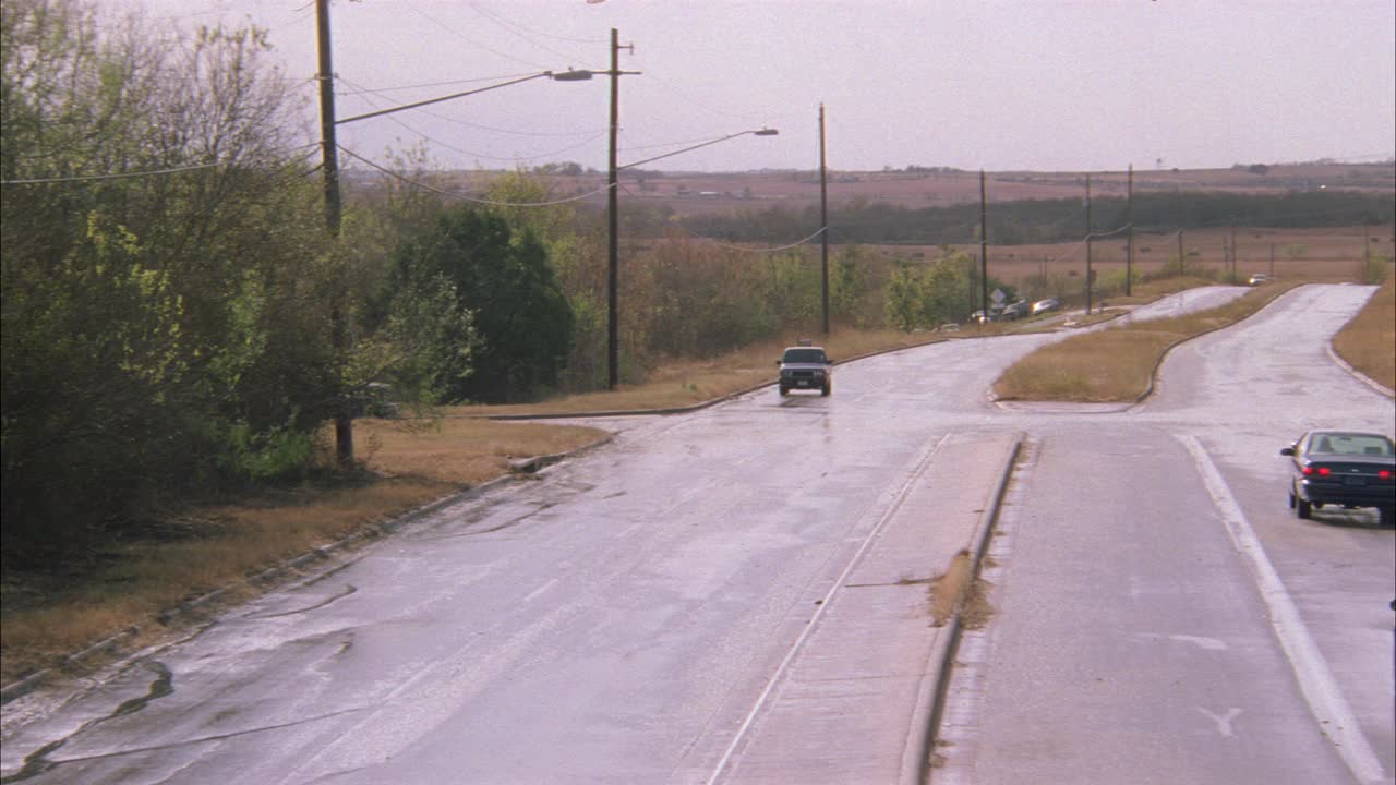 广角的一条乡村公路的交叉口。汽车，小货车，老式的旅游巴士都开过。影片的结尾是指向墨西哥方向的小路标。多云的天空。电线杆、树木。Bus可以用作校车。视频素材