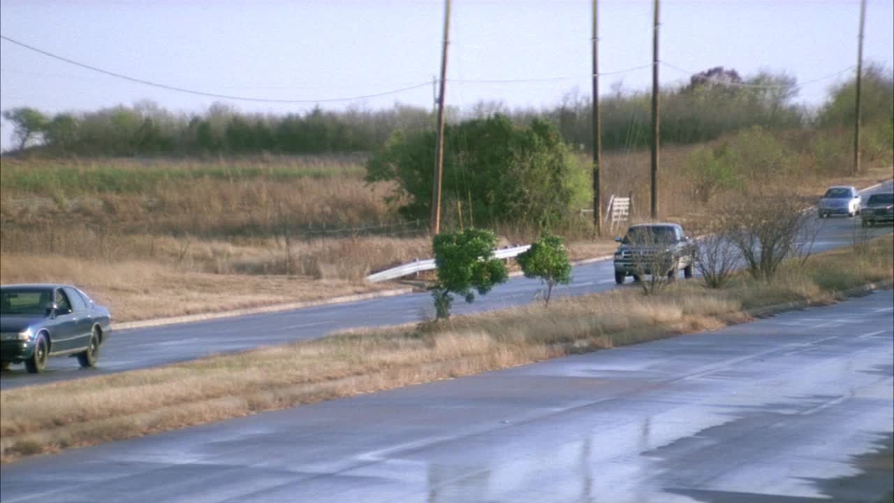 乡村分割乡村道路的跟踪镜头。汽车开过，校车停在路上，切断了一辆80年代早期的汽车，它突然转向，停在了中间位置。另一辆车停下来，司机跑出去检查其他司机是否安全。人们离开了路边视频素材