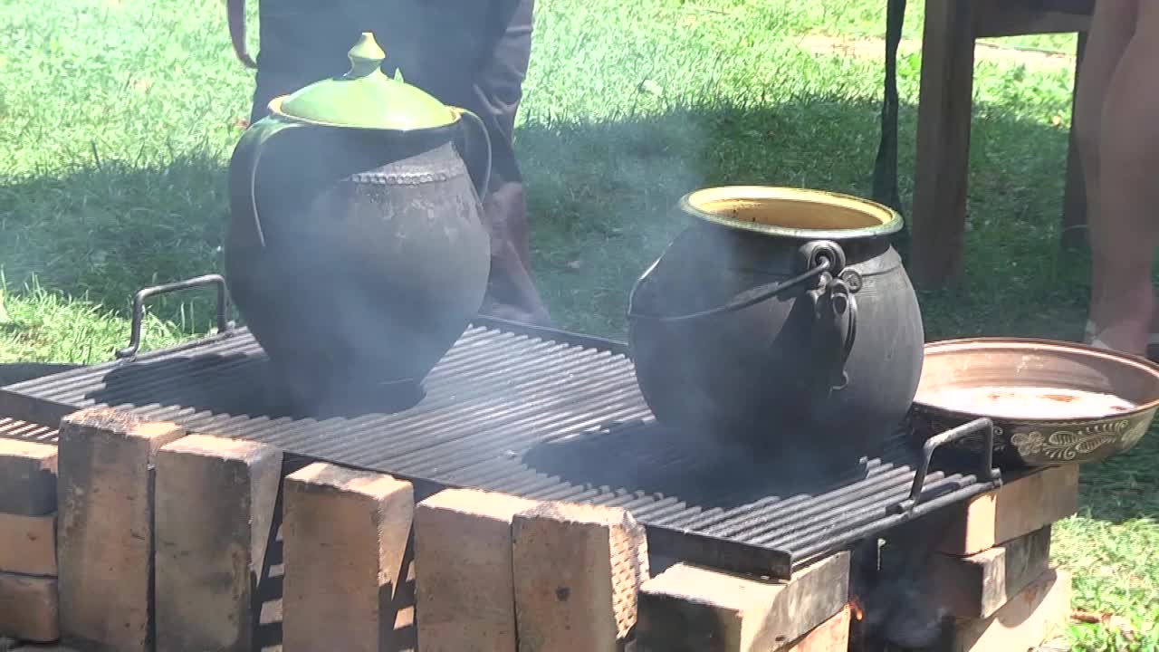 绿色的陶罐被烟熏着，烟是从炉子里冒出来的，用砖头保护着，在上面煮食物视频素材