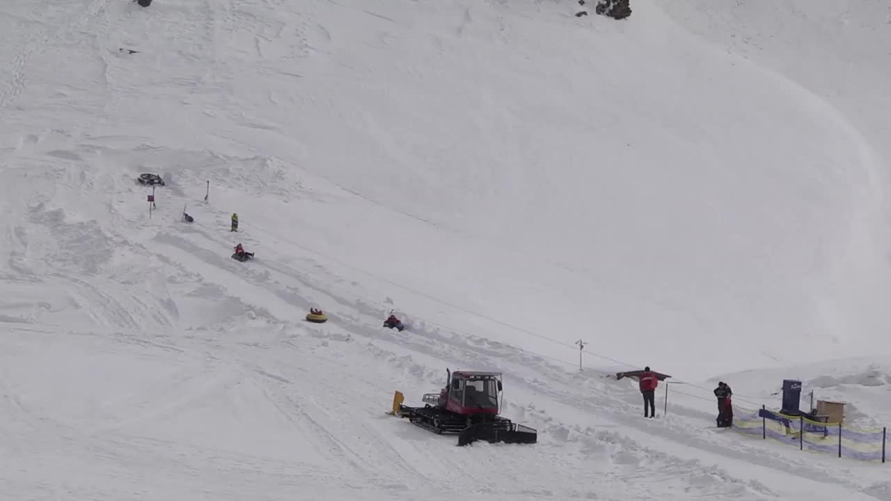 孩子们带着充气汽车摄像机在雪地上行走，他们爬上了坡顶的电缆视频素材