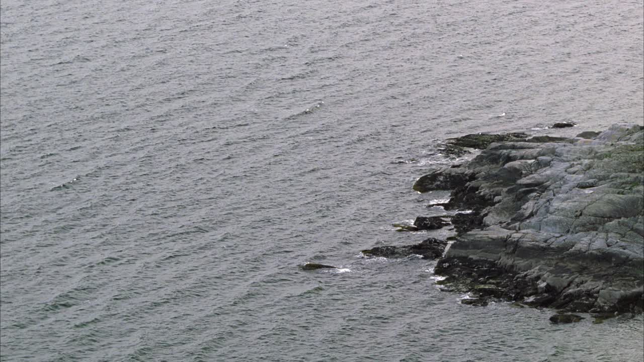 岩石海岸或海岸线的广角。可能是海洋、湖泊或海湾。视频素材