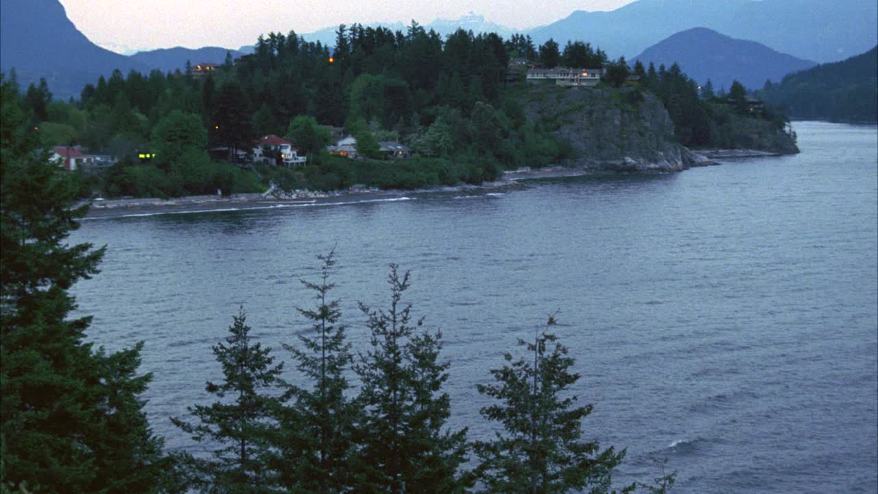 被海湾或湖泊环绕的广角岛屿。可见的海岸线或海岸。房子在岸上。黄昏。bg的山脉和森林。视频素材