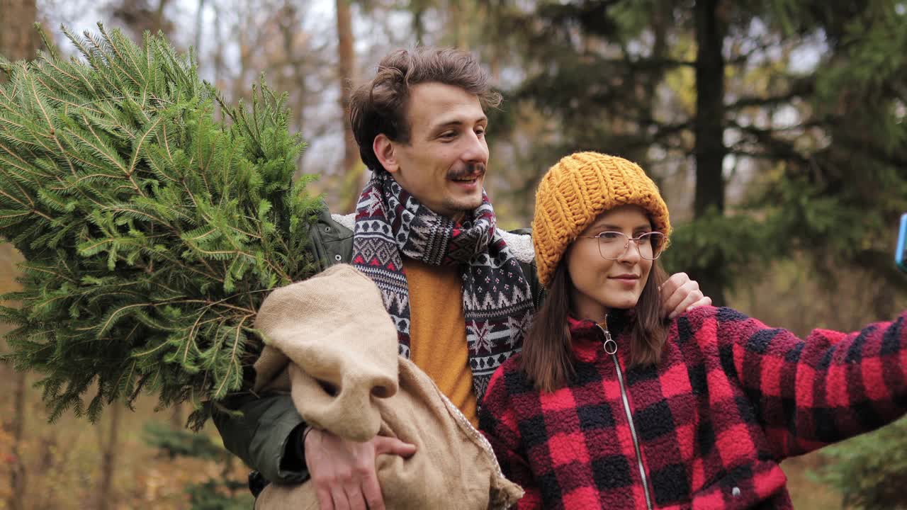 一对夫妇和他们的新圣诞树在一起自拍视频素材