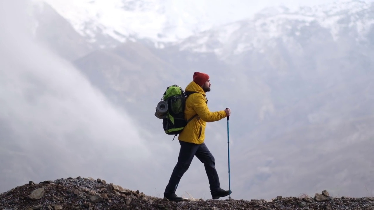 男子登山者站在山顶的山腰上视频素材