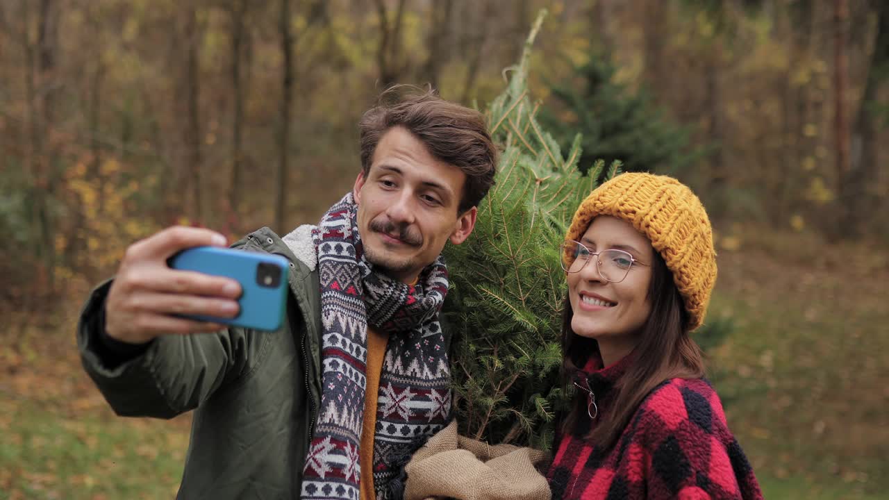 一对夫妇和他们的新圣诞树在一起自拍视频素材