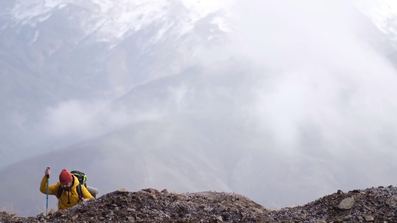 男子登山者站在山顶的山腰上视频素材