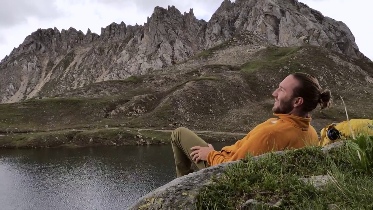 徒步旅行者在山顶上凝视着美丽的山湖视频素材