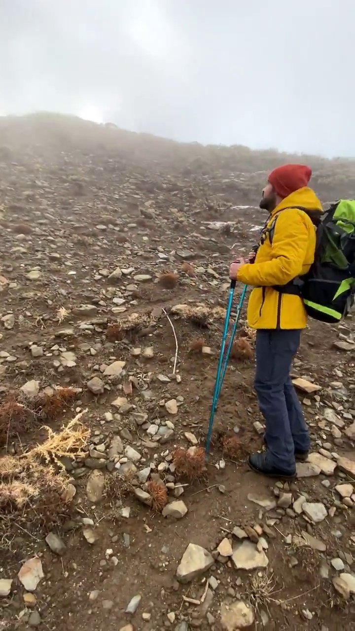 男子登山者站在山顶的山腰上视频素材