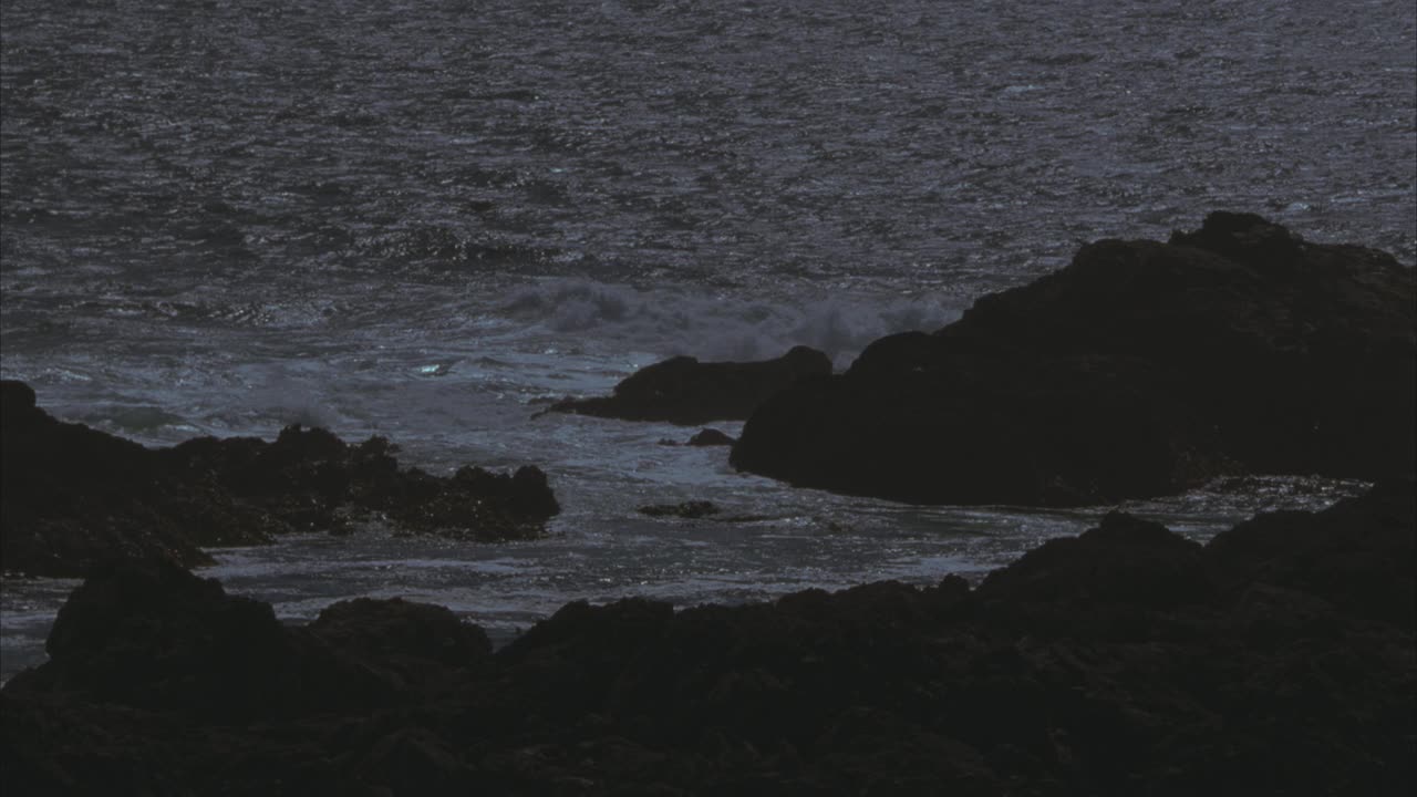 海浪沿崎岖的海岸线撞击岩石的中等角度。海洋。60 FPS。视频素材