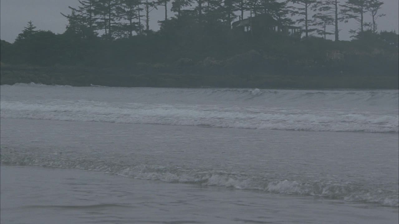 从右到左的海浪撞击海滩或海岸到餐桌上的蜡烛在海浪中设置。餐桌已摆好。镜头继续平移到沙滩上的吊灯上。怪异的。雾蒙蒙的,阴暗的。bg的树木和岩石海岸。超现实主义。视频素材