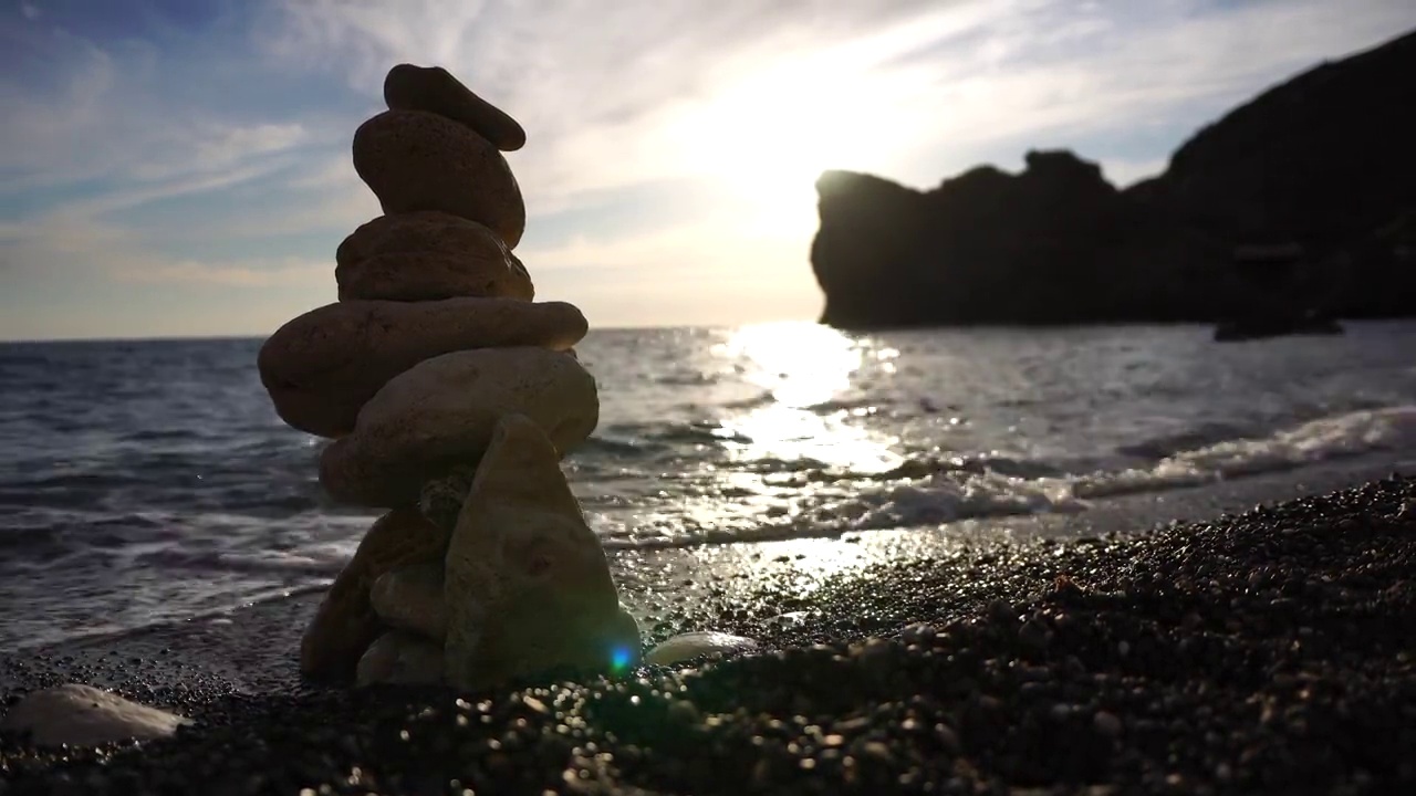 金字塔的石头在一个阳光明媚的日子在蓝色的海洋背景上。节日快乐。卵石滩，风平浪静的大海，旅游胜地。概念上的快乐假期在海上，冥想，水疗，平静视频素材