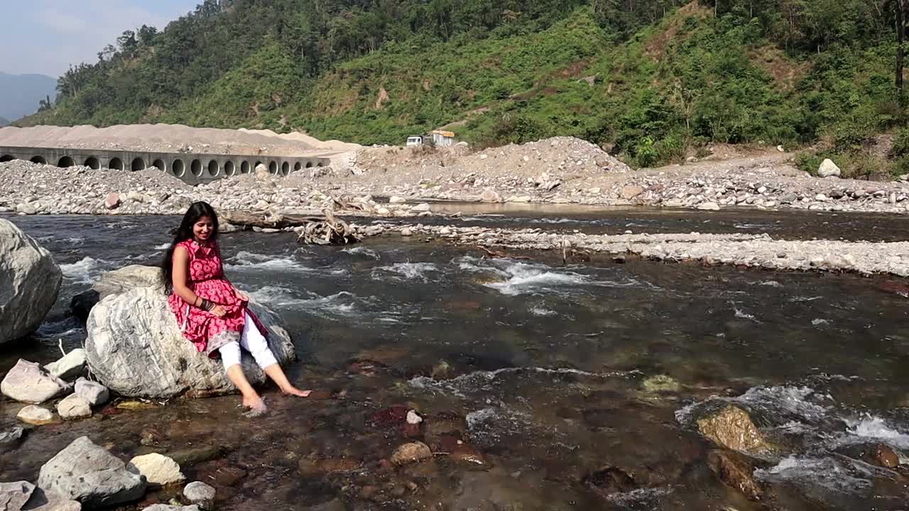 印度北阿坎德邦瑞诗凯诗，一名年轻女子在山上玩流水视频素材