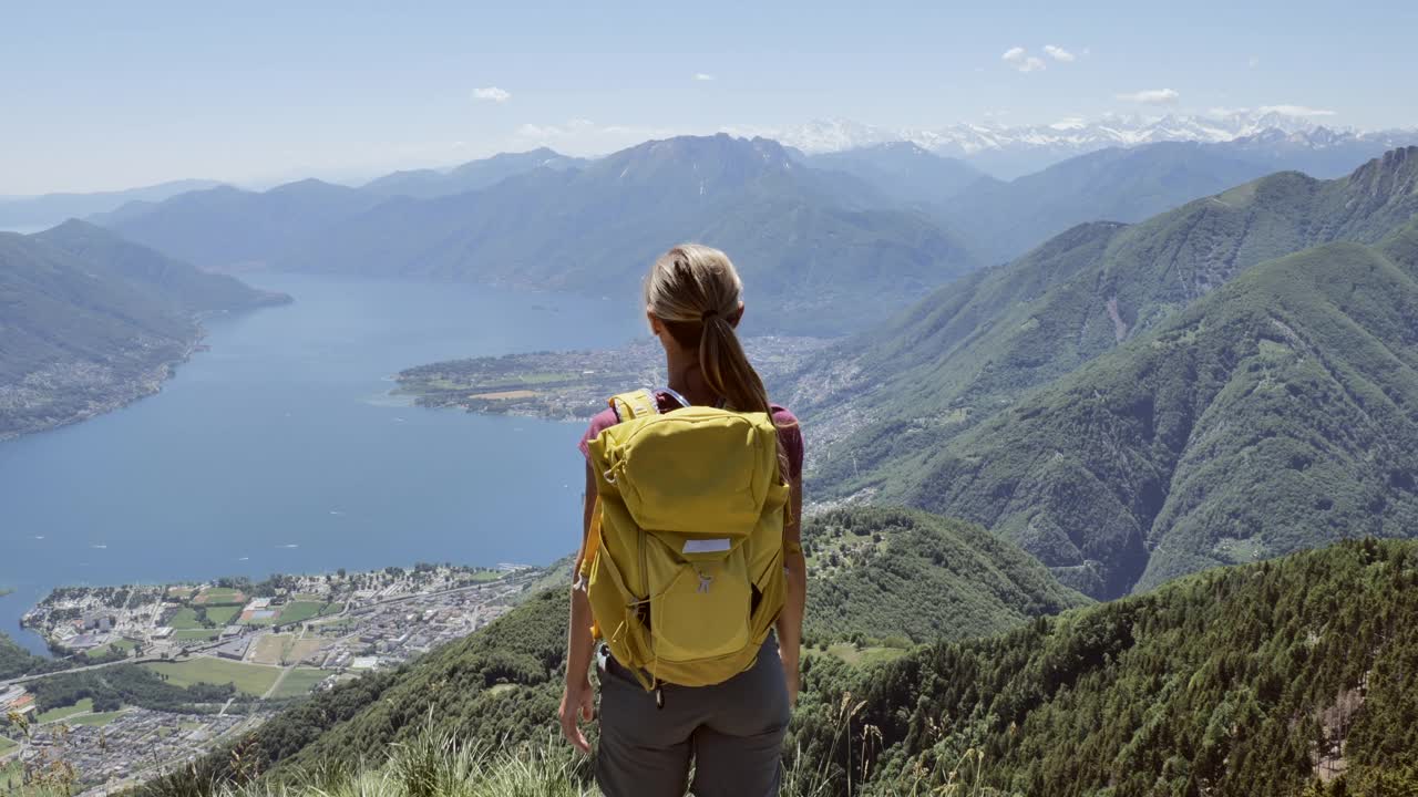 慢动作:一个徒步旅行的年轻女子张开双臂站在山顶上视频素材