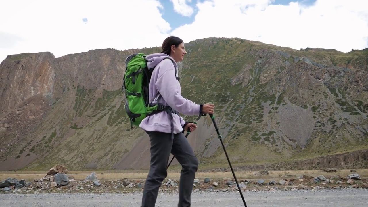 一名女子在落基山脉的地面道路上用登山杖徒步旅行视频素材