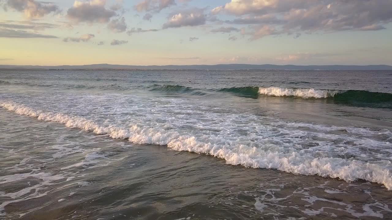 在日落的天空下，蓝色海浪的海面鸟瞰图。视频素材