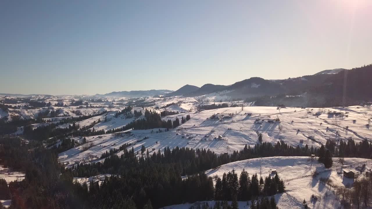 鸟瞰乌克兰喀尔巴阡山脉，冬天白雪覆盖的山坡上散落着房屋。视频素材