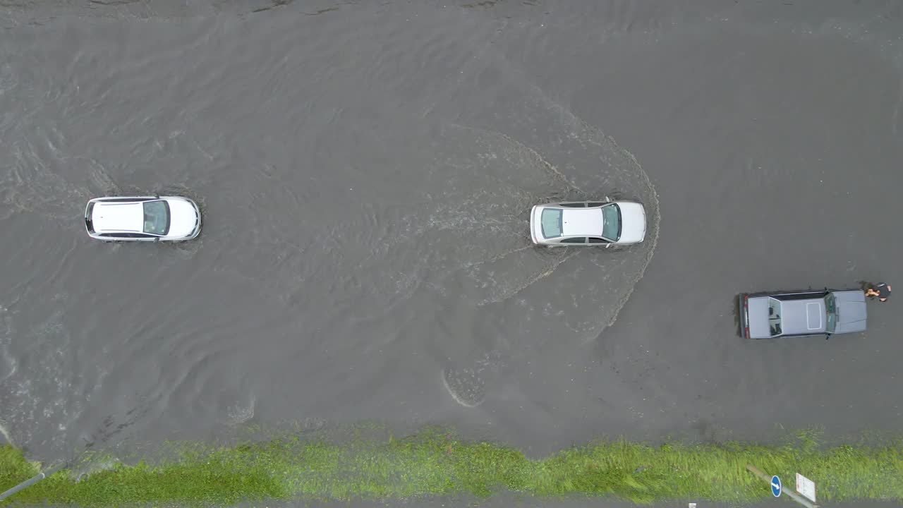 城市交通鸟瞰图，汽车行驶在暴雨后被淹没的街道上。道路排水系统的问题视频素材