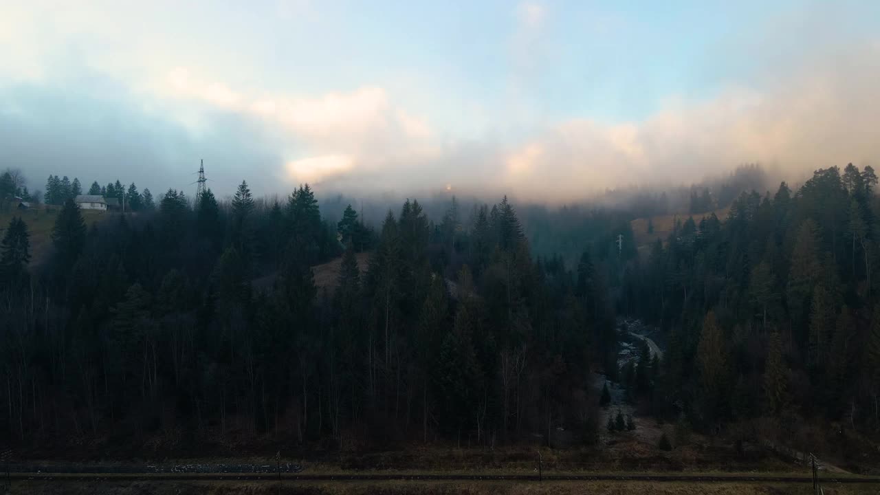 从上面可以看到充满活力的景观，雾蒙蒙的云朵覆盖着群山和日出时的村庄房屋视频素材