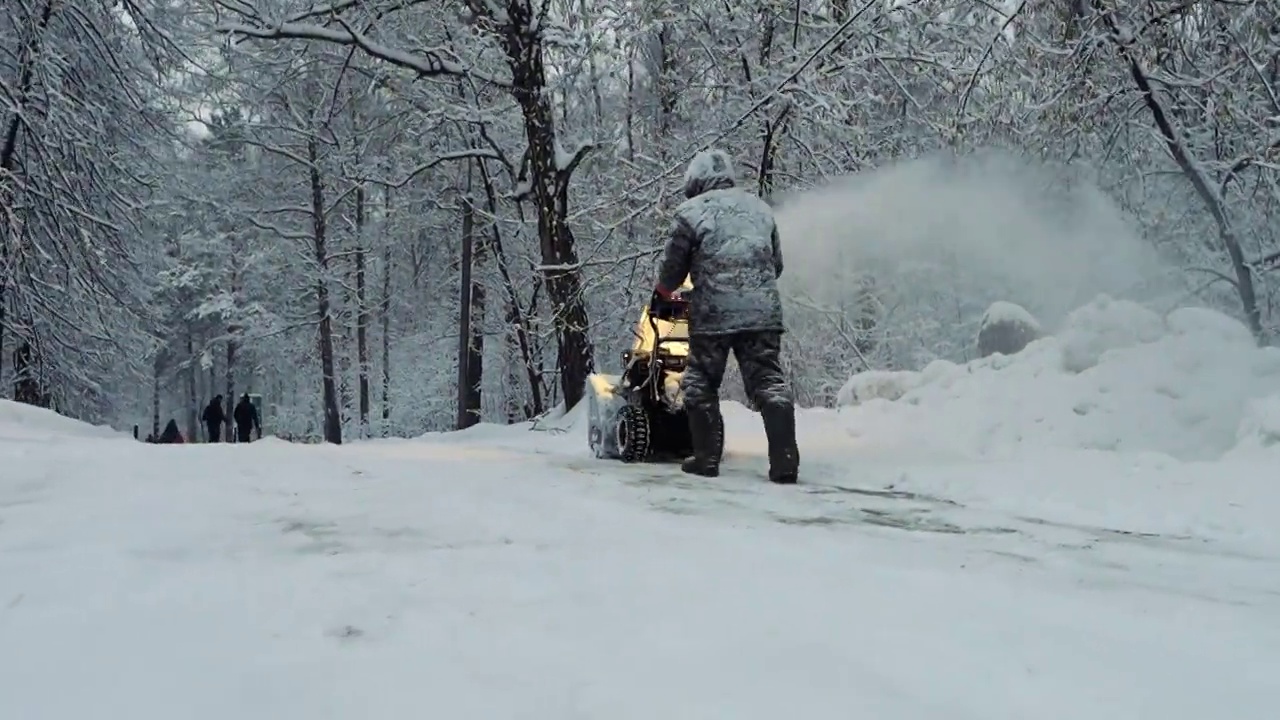 冬天，积雪覆盖的男子用吹风机和除雪设备清洁道路视频素材