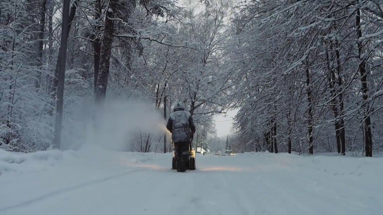 冬天，积雪覆盖的男子用吹风机和除雪设备清洁道路视频素材