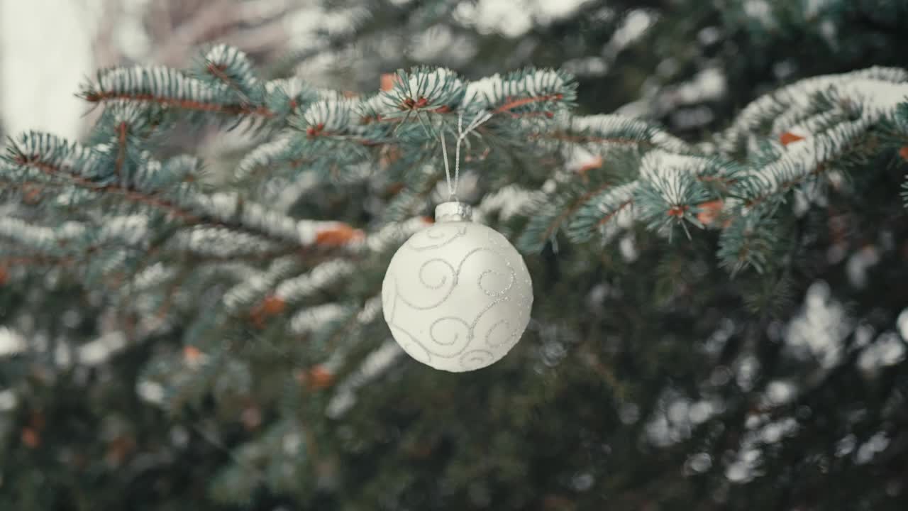 雪中的圣诞树枝上的白色球视频素材