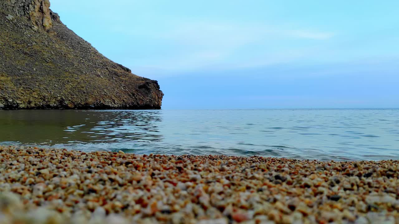 特写，贝加尔湖沙滩，清澈清澈的湖水。湖滨的沙粒五彩缤纷，水波荡漾。湖岸依山傍水，自然景观优美。4 k, ProRes视频素材