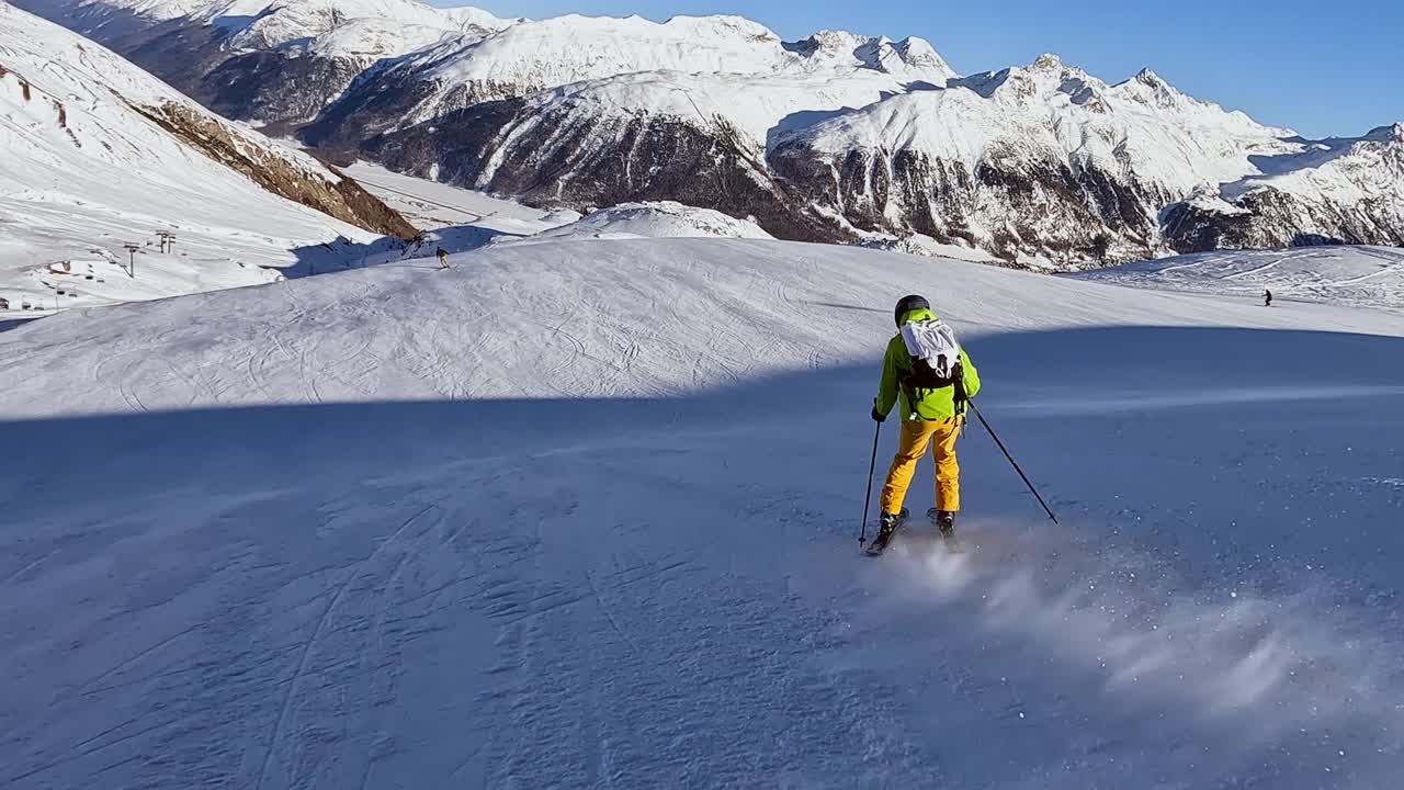 (下图)，一个年轻人在阿尔卑斯山的滑雪坡上滑雪。动作摄像机拍摄滑雪者下降技术道视频素材