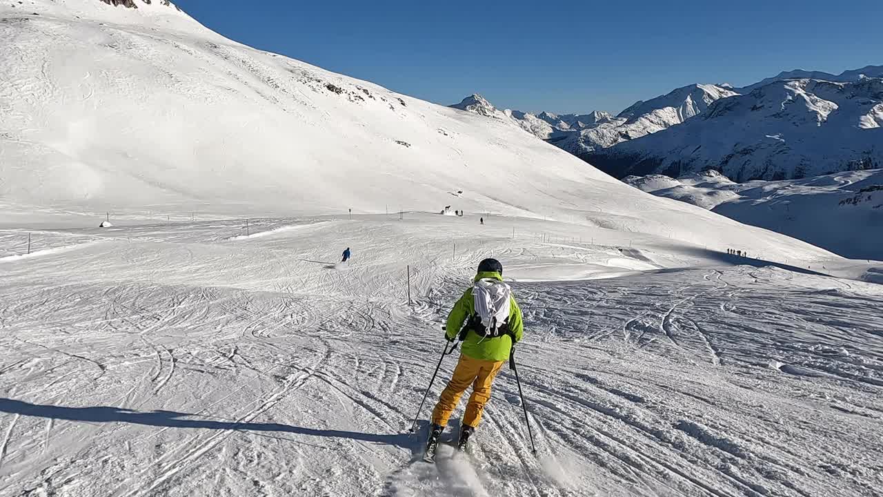 慢镜头:一个年轻人在阿尔卑斯山的滑雪坡上滑下坡视频素材