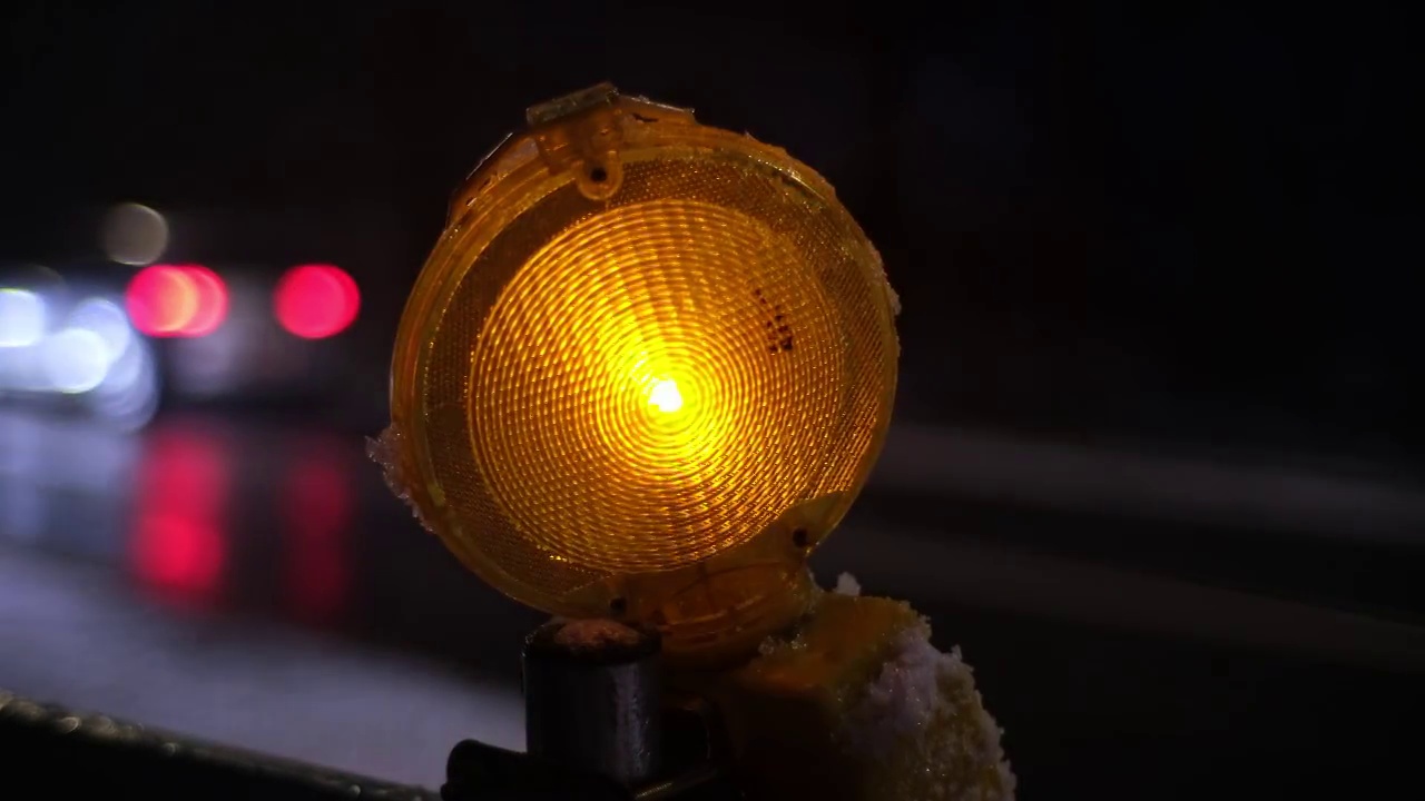 在冬季夜晚，由于冰路繁忙，交通十分挤塞，维修道路工程路障橙色警示灯相继闪烁视频素材