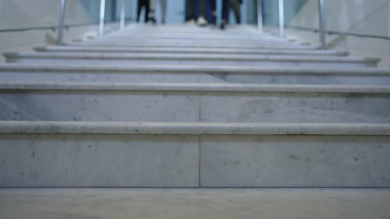 办公室楼梯的特写，人们匆忙下楼的脚步声。忙碌的男男女女在屋里跑来跑去。业务和守时的理念。视频素材