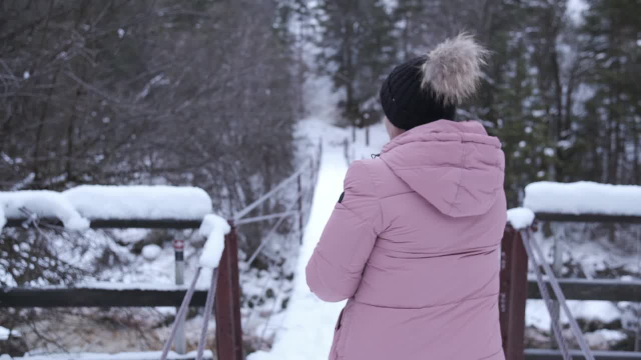 一个女人在白雪覆盖的桥上慢慢地走着视频素材