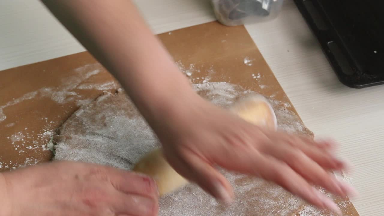 一位妇女用擀面杖擀开姜饼面团。制作雪花和星星形状的姜饼。特写镜头。视频素材