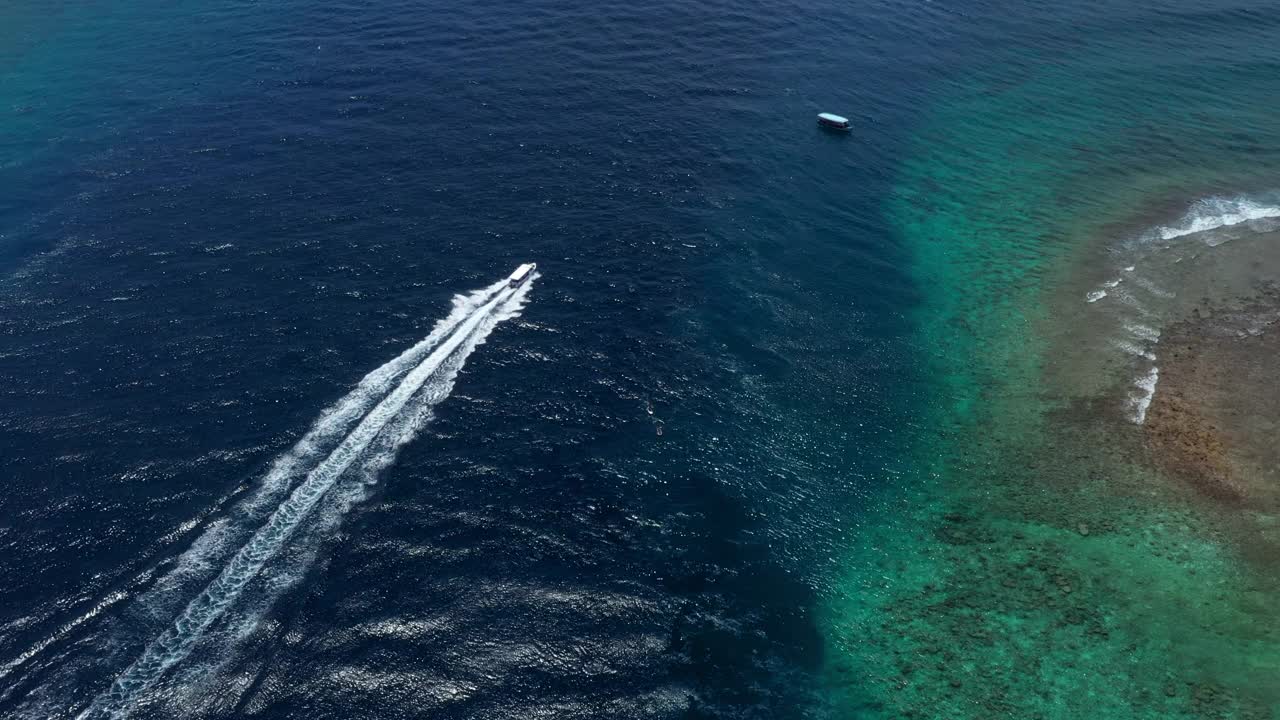 空中前进风景镜头的船在蓝色的海中移动，无人机飞行在阳光明媚的一天-马尔代夫，马尔代夫视频素材