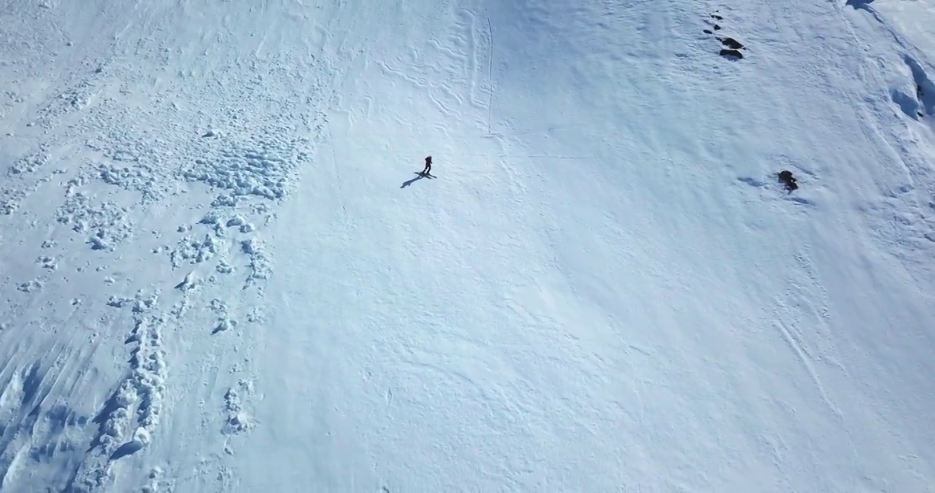 男性游客在雪景上滑雪的空中平移镜头，无人机在阳光明媚的日子里向后飞行-阿拉斯加内陆，阿拉斯加视频素材