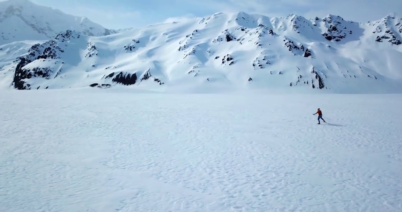 男性游客在雪景上滑雪的空中前摇镜头，无人机在阳光明媚的一天飞行-阿拉斯加内陆，阿拉斯加视频素材