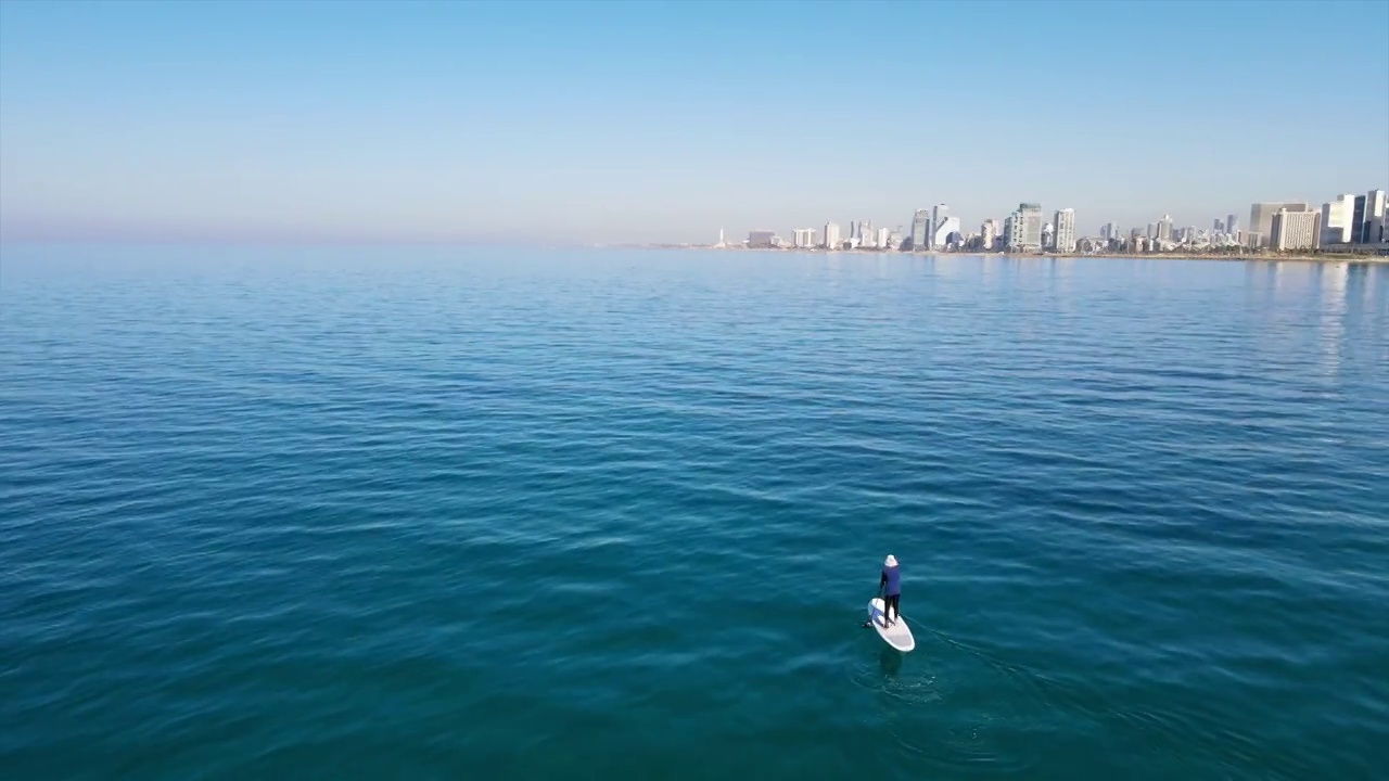 空中拍摄的男子游客在阳光明媚的一天在海上划桨冲浪-特拉维夫，以色列视频素材