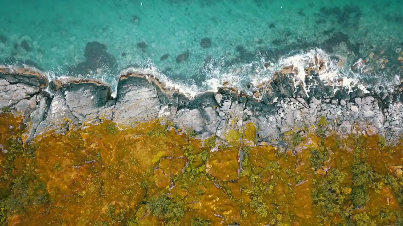 空中顶部封锁风景镜头浪花飞溅在景观上，鸟飞过蓝绿色的海-特罗姆瑟市，挪威视频素材