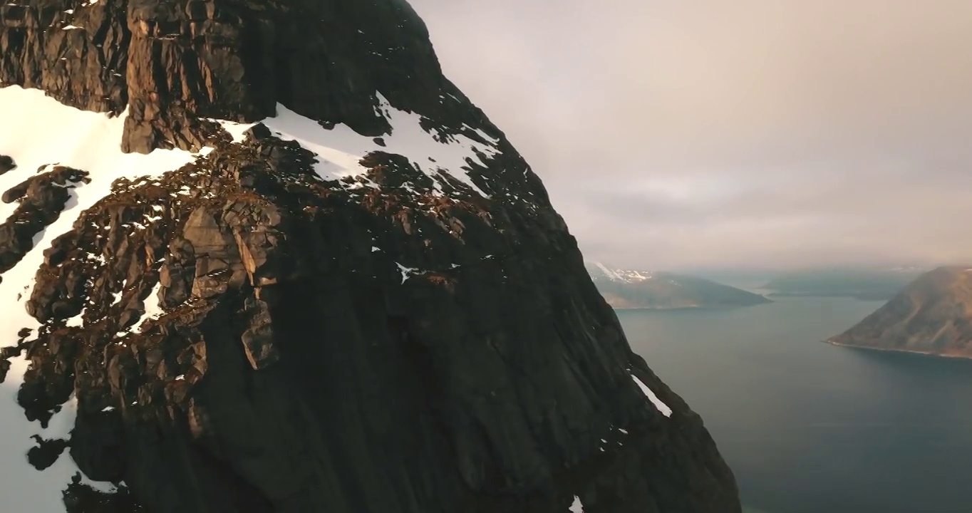 空中平移雪山岩层的风景镜头，无人机在海上的景观上空飞行-特罗姆瑟市，挪威视频素材